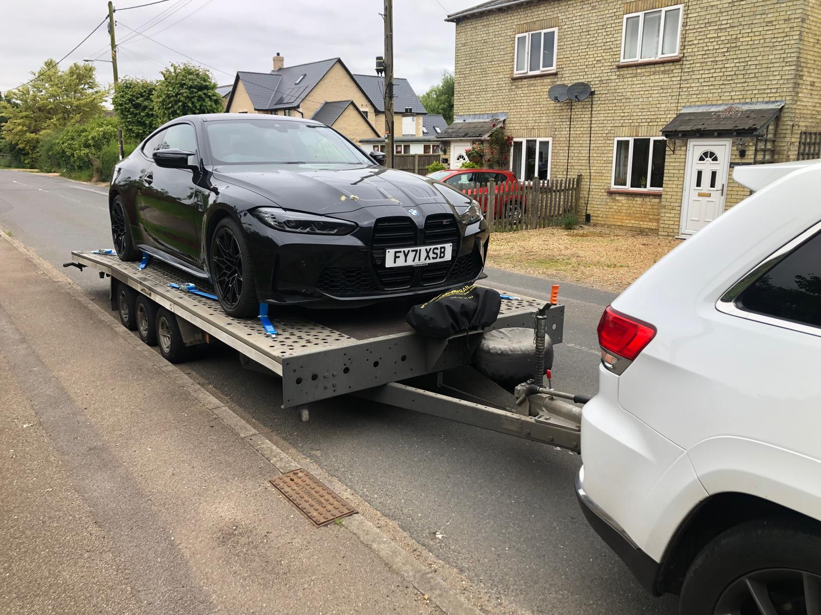 BMW M4 coupe on flatbed trailer in residential area