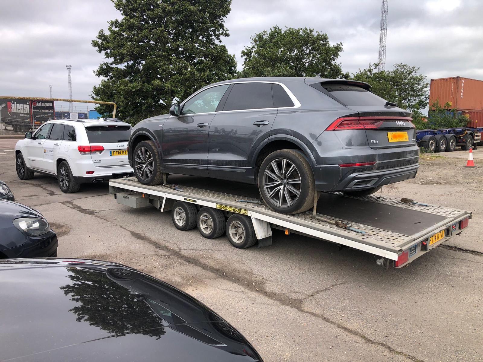 Audi Q8 on flatbed trailer at dealership yard