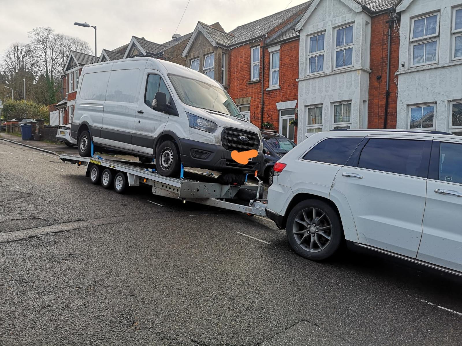 White Ford Transit van on flatbed trailer