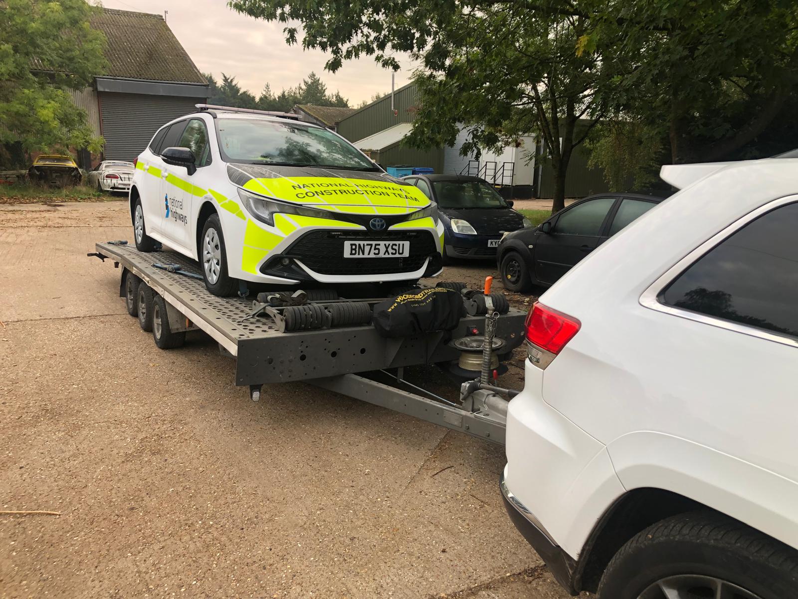 White Toyota construction vehicle on flatbed trailer